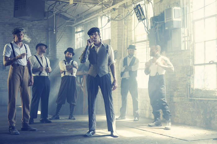 The crew standing in a daylit factory room, smoke in the windows
