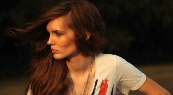 The model in a white shirt with layered necklaces, her hair blowing
