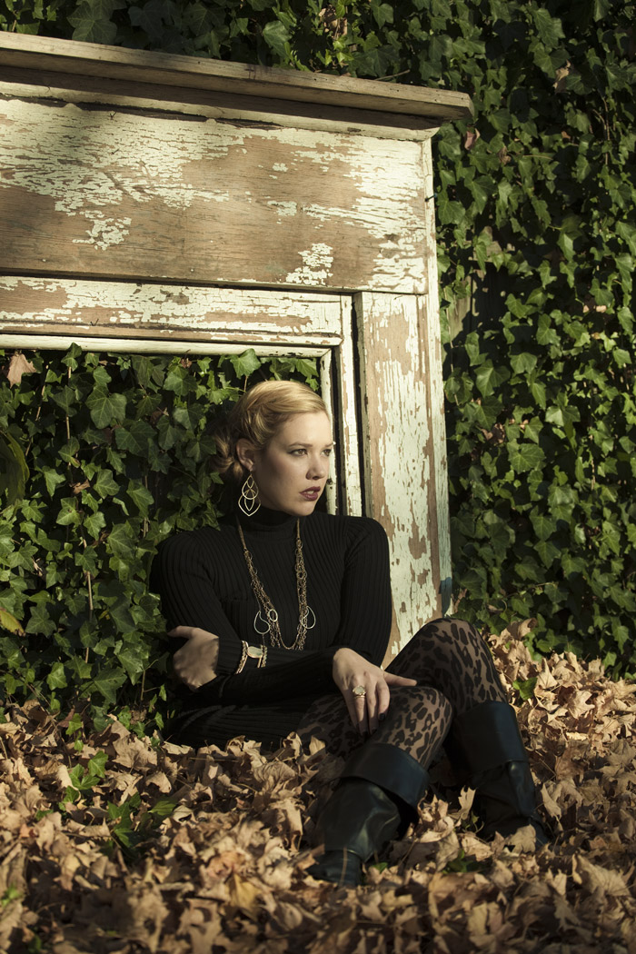 Model seated in leaves in front of a weathered mantel